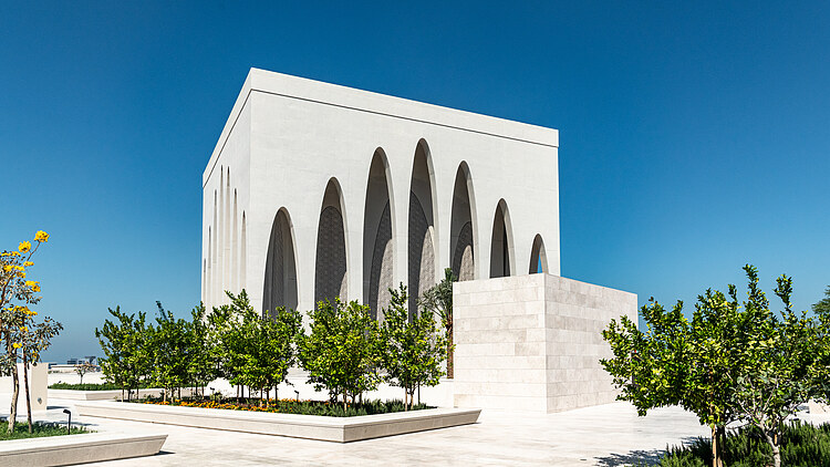 Modernes Gebäude des Abrahamisches Familienhaus auf der Insel Saadiyat mit markanter weißer Architektur, hohen Rundbögen und begrüntem Vorplatz unter klarem blauen Himmel