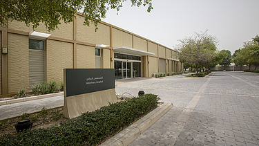 Entrance area of the Al Shaqab Equine Veterinary Medical Centre, featuring the veterinary facility building, access road, and clinic signage