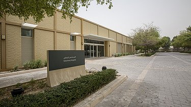 Entrance area of the Al Shaqab Equine Veterinary Medical Centre, featuring the veterinary facility building, access road, and clinic signage