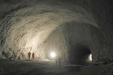 Illuminated cave with three miners