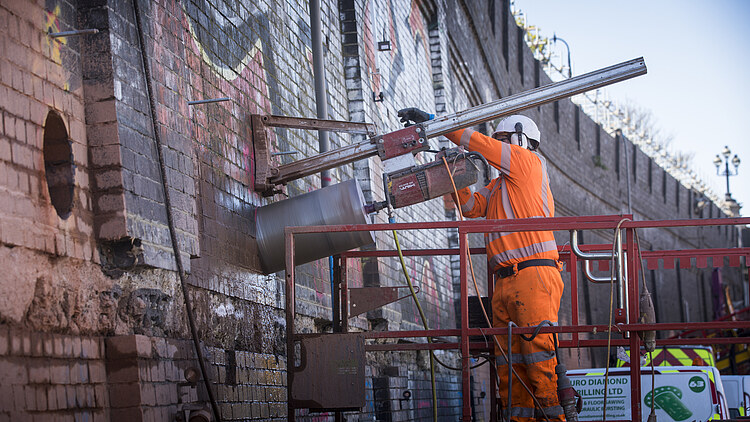 Construction work on a brick wall of the HS2 tunnel using a core drilling rig mounted on a work platform