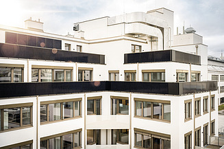 Modernes, fertiggestelltes Bürogebäude mit heller Fassade, großzügigen Fensterflächen und Solarpanelen als Beispiel für schlüsselfertiges Bauen