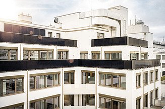 Modernes, fertiggestelltes Bürogebäude mit heller Fassade, großzügigen Fensterflächen und Solarpanelen als Beispiel für schlüsselfertiges Bauen