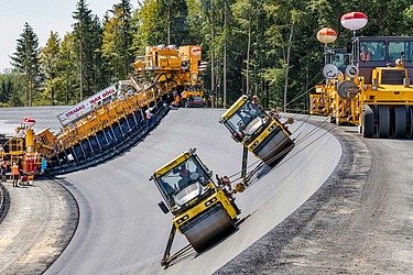 Two rollers work on a steep asphalt curve