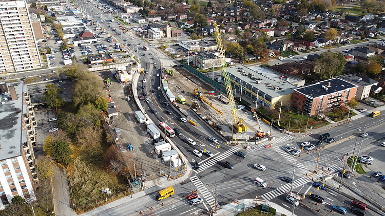 Tunnel excavation works for the Scarborough Subway Extension at an urban intersection, featuring a large crane and surrounding traffic