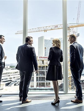 Vier Führungskräfte die aus einem Fenster blicken