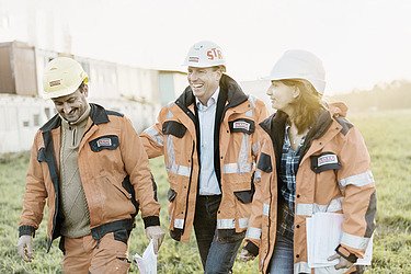 Two men and a woman from the engineering team on a meadow