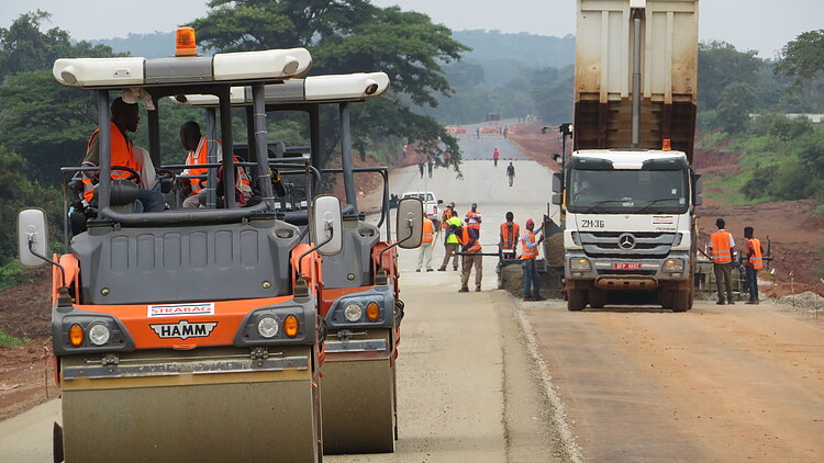 Road rollers, construction vehicles and work crews constructing a new roadway, including pavement compaction and road infrastructure works.way