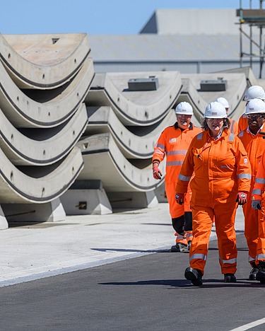 Six workers walk next to precast concrete elements