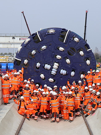 A team of tunnel workers in front of a large tunnel boring machine