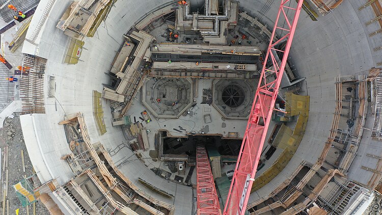 Senkrechter Bauschacht im Tunnel- und Untertagebau mit Schalung, Kran und Baustelleneinrichtungen während der Herstellung der Schachtstruktur.