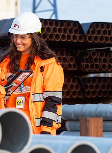 Two female construction workers on a construction site with large pipes