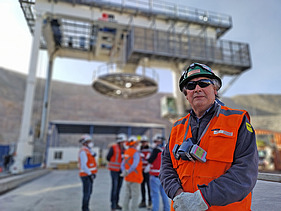 Mining site at the Chuquicamata Underground Mine Development project, showing a shaft hoisting structure, personnel in safety gear, and mine infrastructure in the background