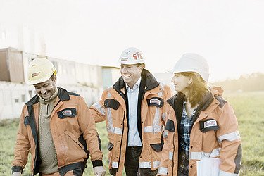 Two men and a woman from the engineering team on a meadow